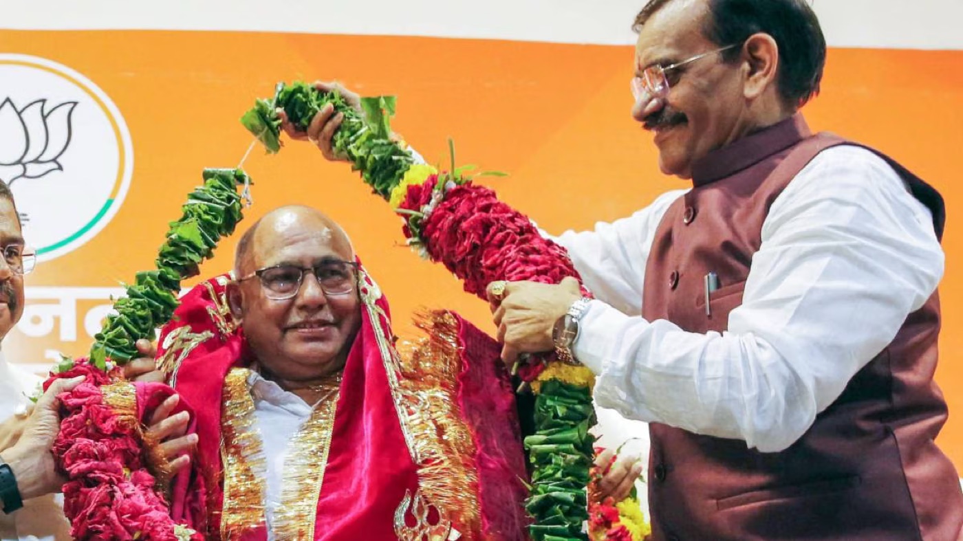Hemant Khandelwal being garlanded on stage by a senior party leader